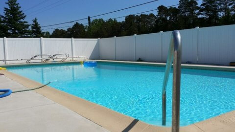 View of heated pool near hotel rooms with large privacy fence. © Frank Rogala.