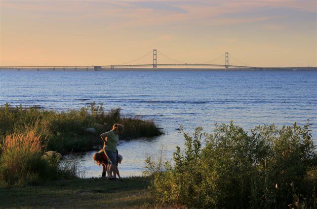 Photo of campers skipping stones with a view of the Mackinac Bridge at Mackinaw Mill Creek Camping in Mackinaw City, MI. © 2016 Frank Rogala.