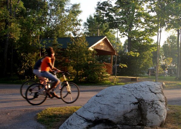 Photo of campers riding bikes near Big Rock at Mackinaw Mill Creek Camping in Mackinaw City, MI. © 2016 Frank Rogala.