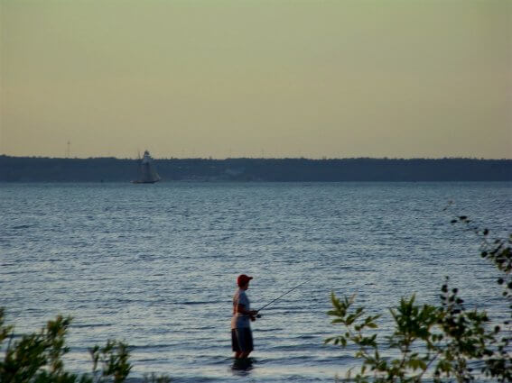 Photo of a schooner on the shore while man fishes in Lake Huron from the shores of Mackinaw Mill Creek Camping in Mackinaw City, MI. © 2016 Frank Rogala.