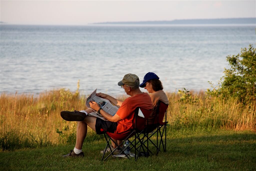Photo of a camping couple reading the newspaper on the shores of Mackinaw Mill Creek Camping in Mackinaw City, MI. © 2016 Frank Rogala.